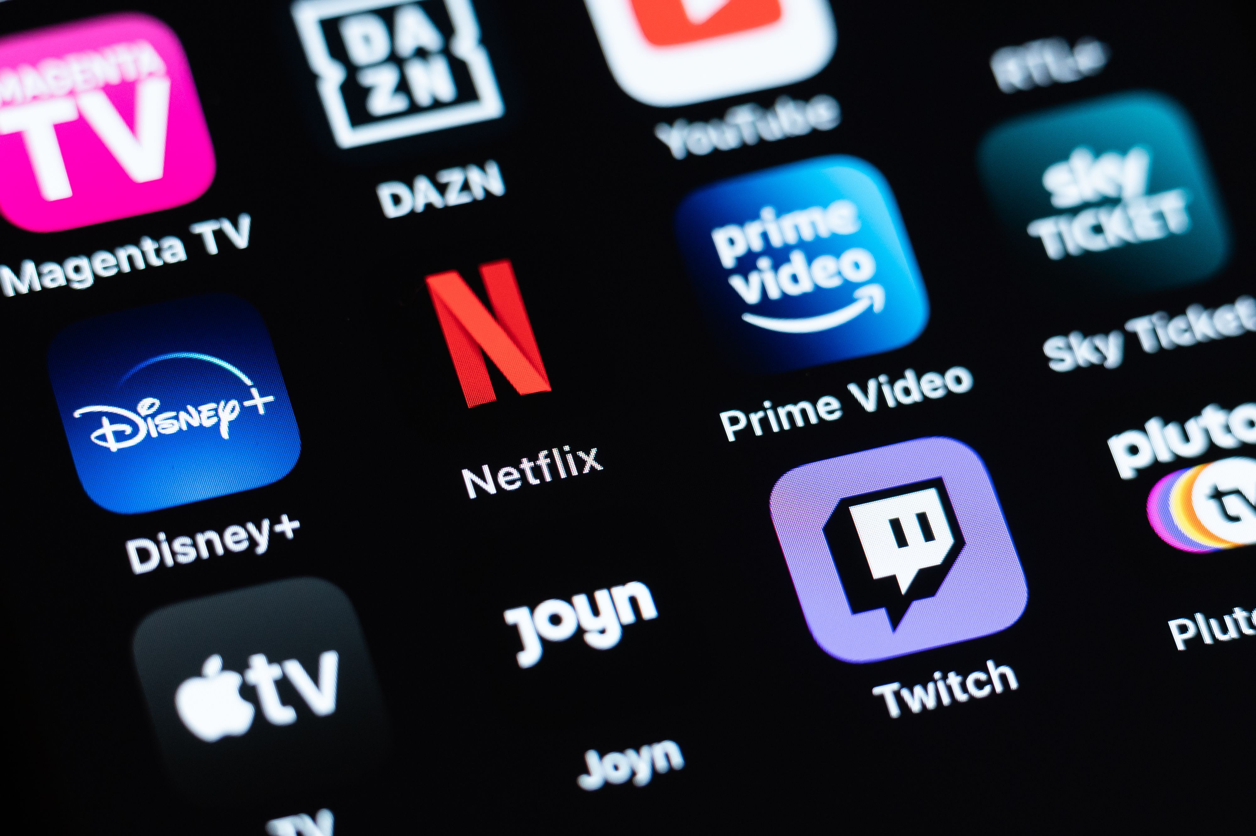 Verschiedene Streaming-Dienste, darunter Magenta TV, DAZN, YouTube, Disney+, Netflix, Prime Video, Sky Ticket, Aplle TV, Joyn, Twitch, sind auf einem Bildschirm zu sehen.