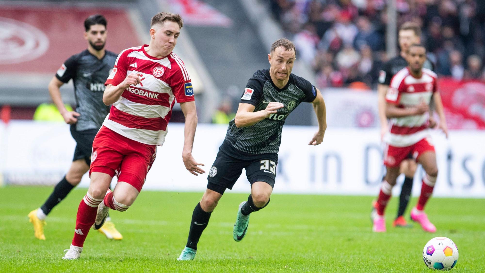 Isak Johannesson und Maurice Neubauer rennen im Sprint um den Ballgewinn über den Platz.