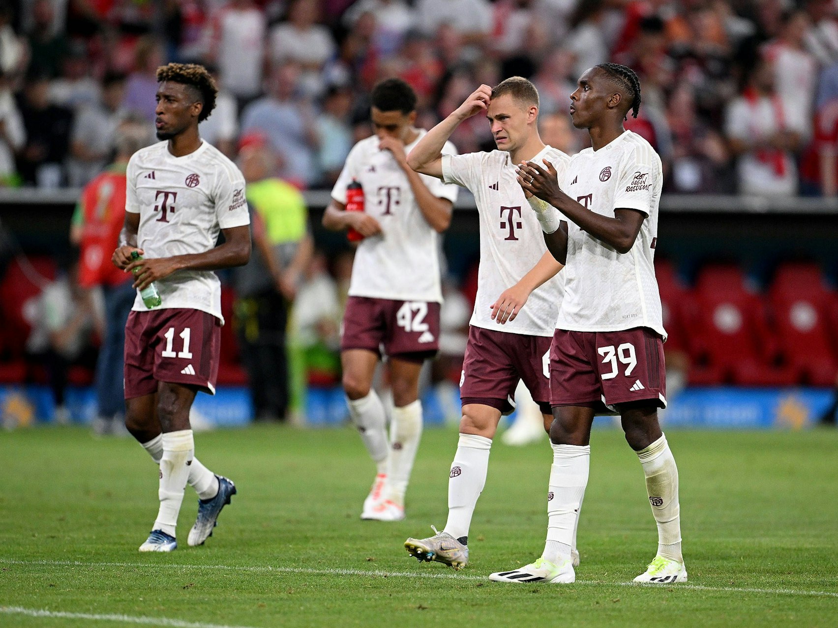 Kingsley Coman (l.), Joshua Kimmich und Mathys Tel (r.) gehen nach dem Spiel in Richtung Fan-Kurve.
