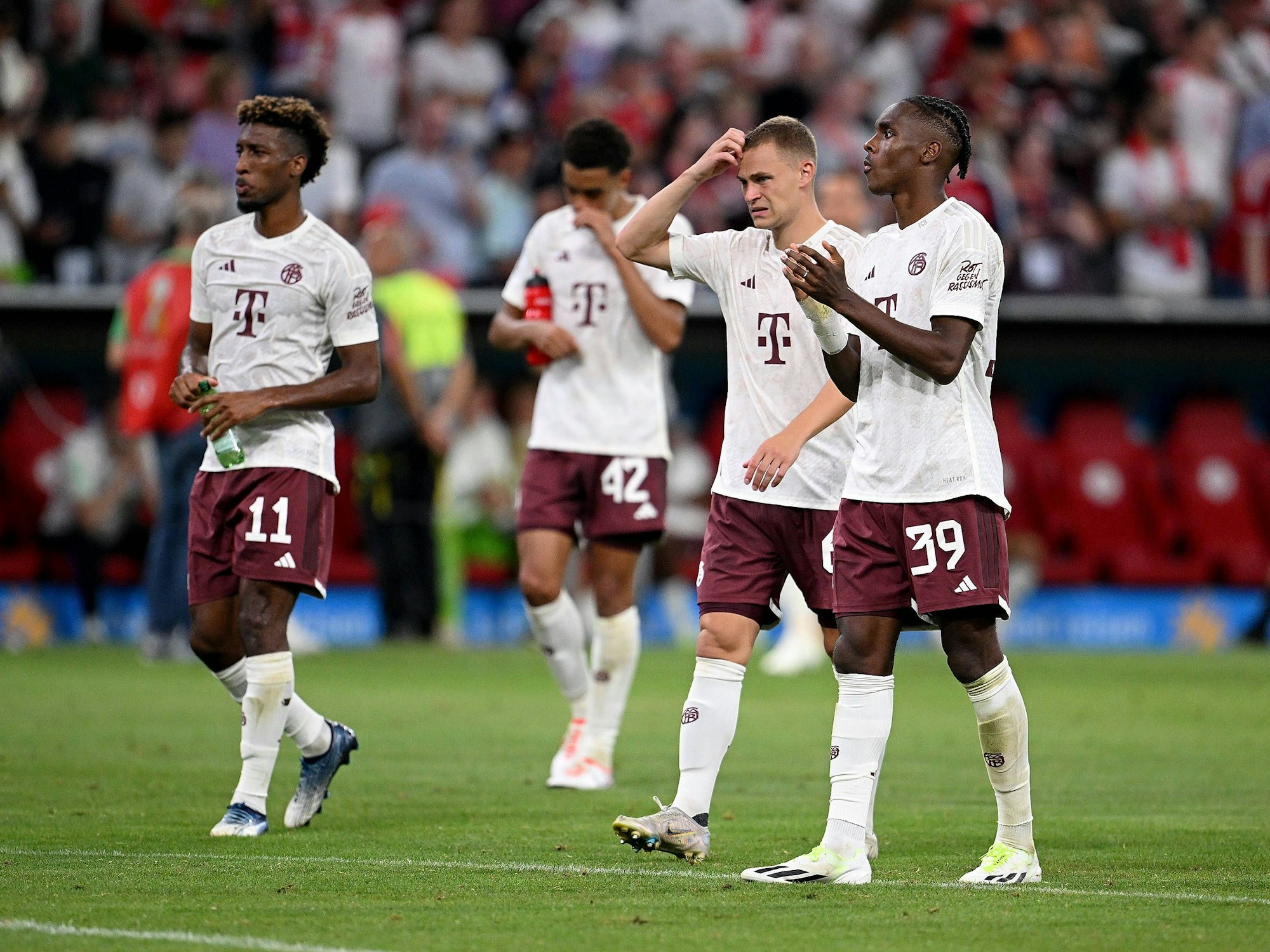 Kingsley Coman (l.), Joshua Kimmich und Mathys Tel (r.) gehen nach dem Spiel in Richtung Fan-Kurve.