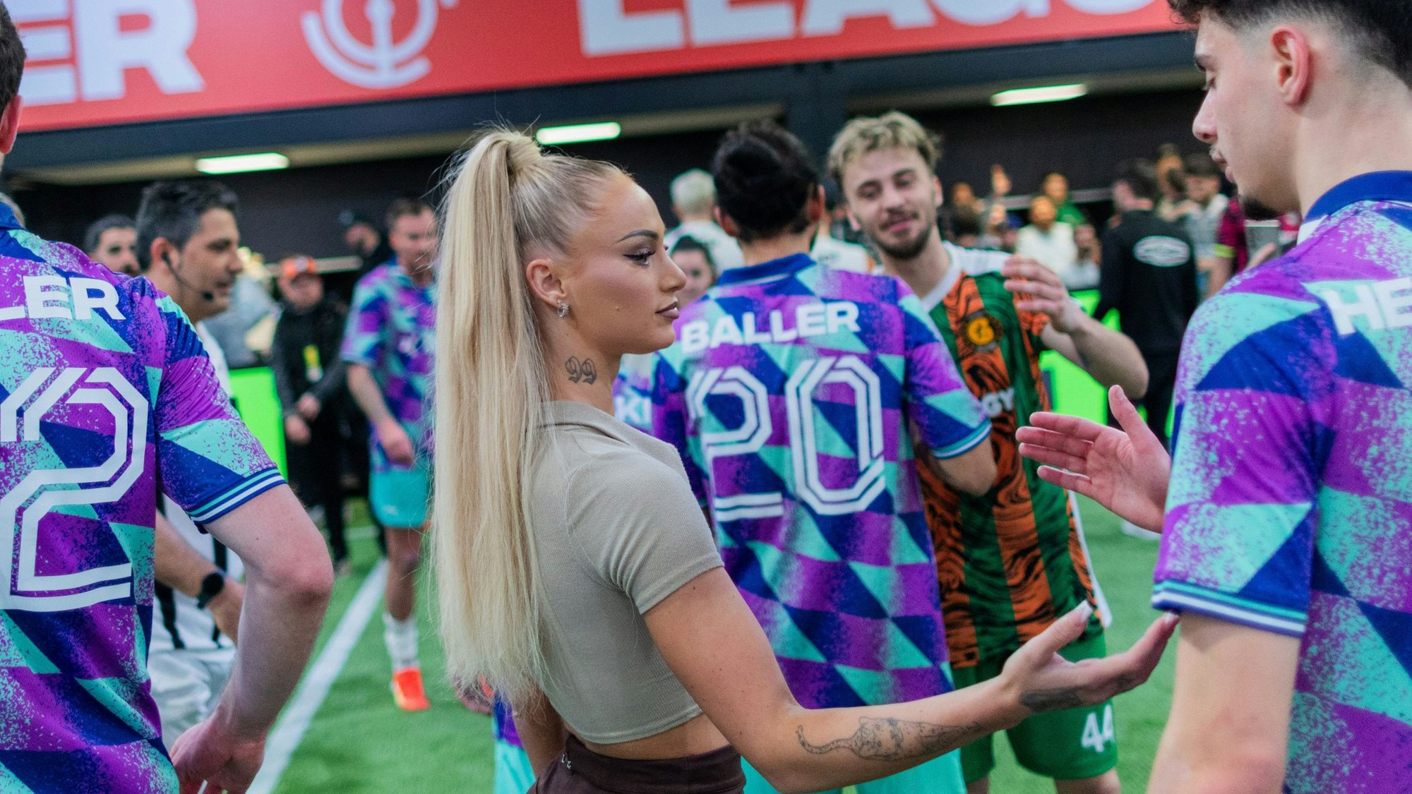 Alisha Lehmann, Fußball Nationalspielerin der Schweiz und Spielerin bei Aston Villa, Team-Managerin von „Streets United“, steht bei der Baller League nach dem Spiel mit ihrem Team zusammen auf dem Spielfeld in der Motorworld in Köln.
