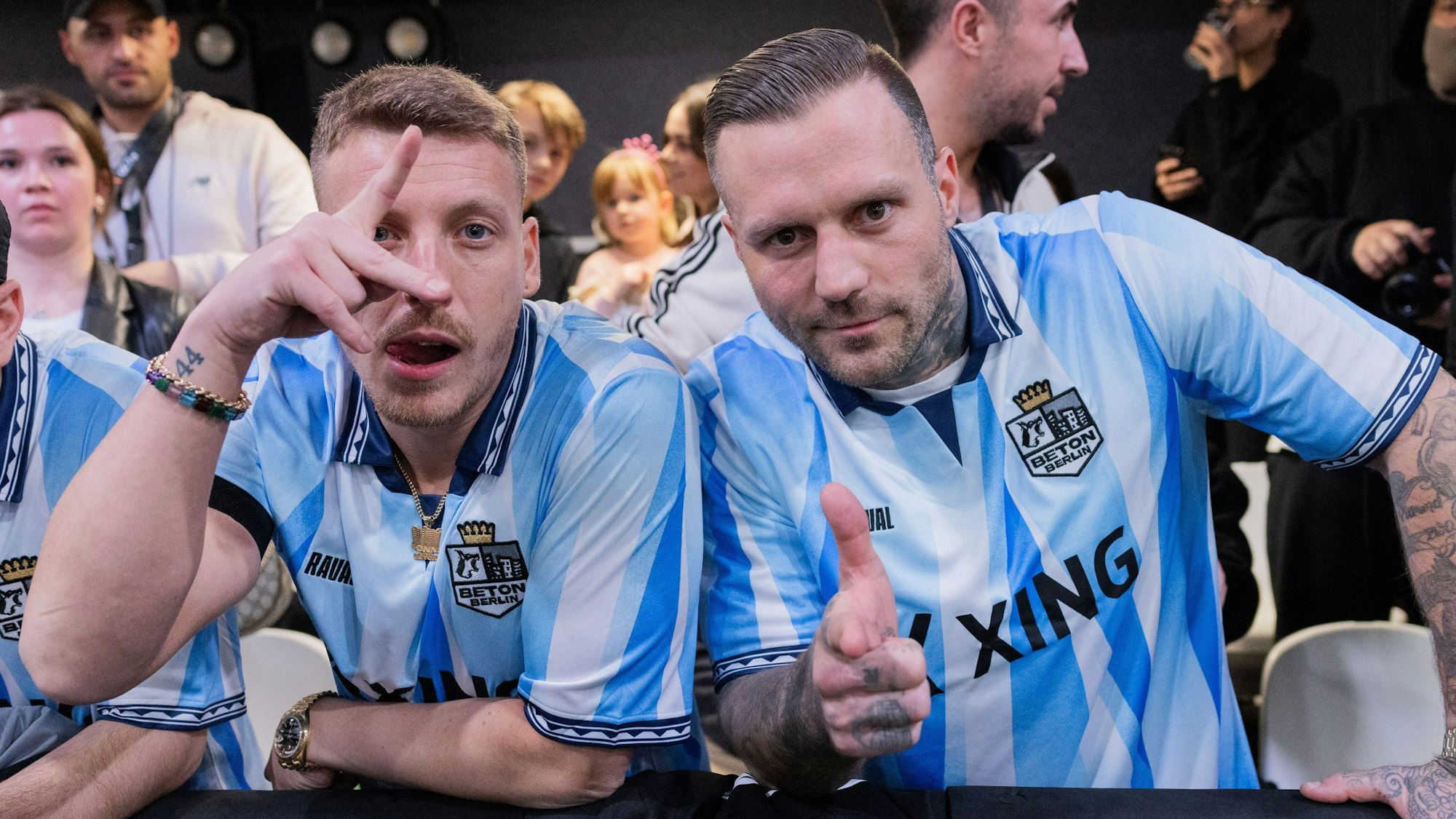 Felix Lobrecht (l), Comedian, und Kontra K, Rapper, stehen als Team-Manager des Teams Beton Berlin an der Bande des Spielfeldrands in der Motorworld.
