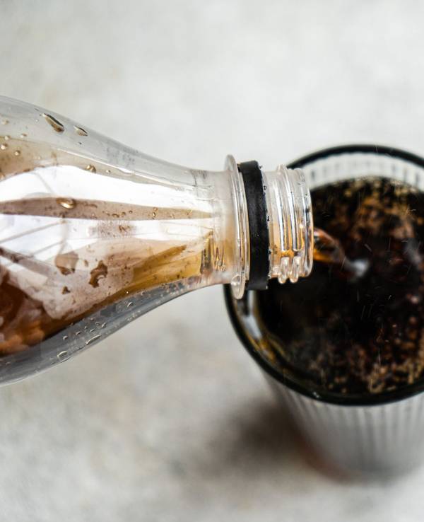 Auf dem Foto wird Cola in ein Glas eingeschenkt.