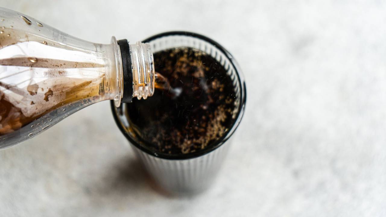 Auf dem Foto wird Cola in ein Glas eingeschenkt.