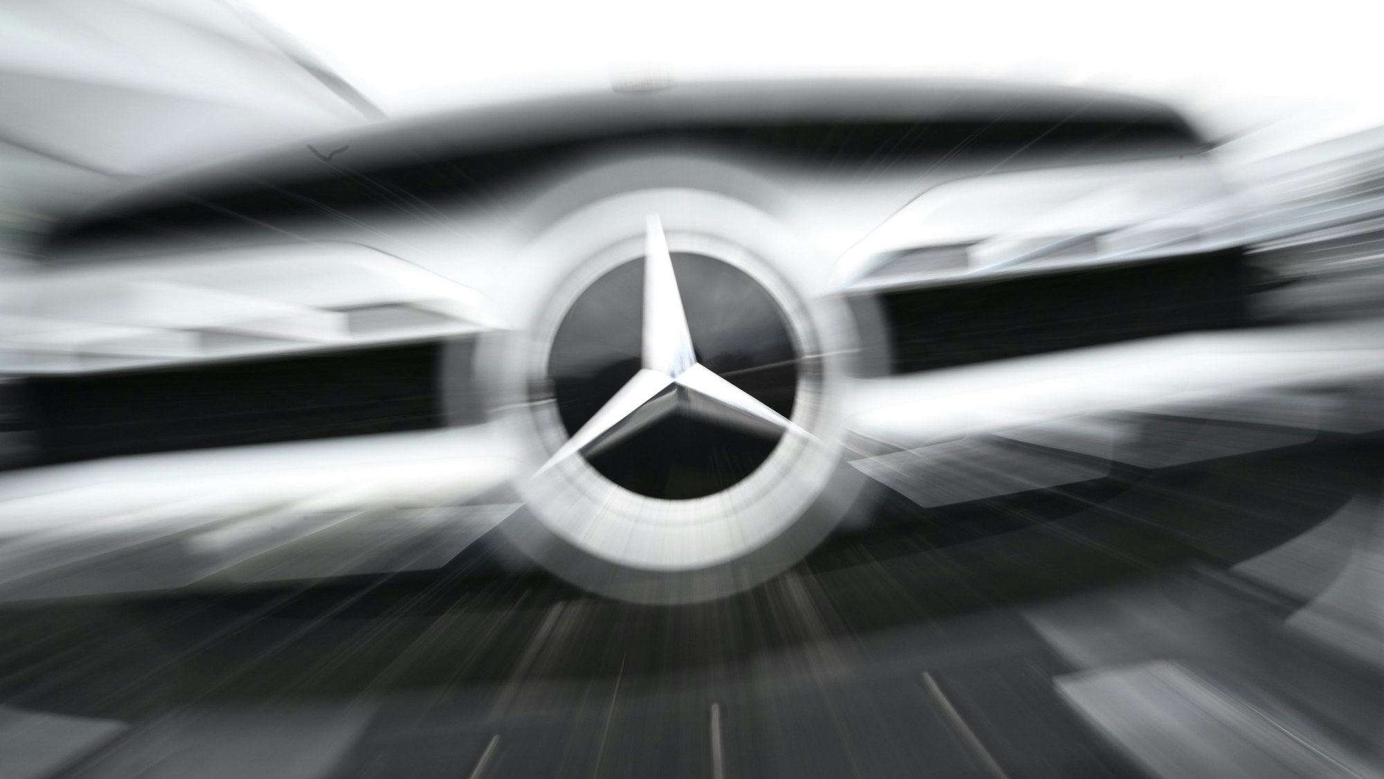 Das Logo der Automarke Mercedes-Benz ist an der Front eines Mercedes-Benz Fahrzeugs angebracht (Wischeffekt durch Langzeitbelichtung und Zoomen).