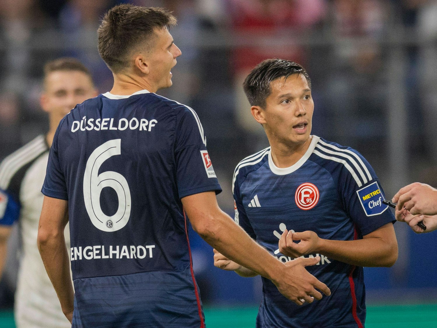 Die Düsseldorf-Profis Yannik Engelhardt und Shinta Appelkamp sprechen während des Spiels beim Hamburger SV mit dem Schiedsrichter.