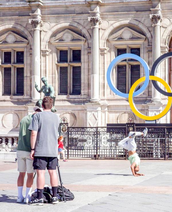 Ein Breakdancer tanzt vor den Olympischen Ringen am Rathaus von Paris.