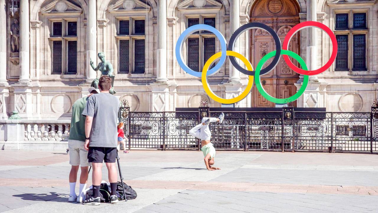Ein Breakdancer tanzt vor den Olympischen Ringen am Rathaus von Paris.