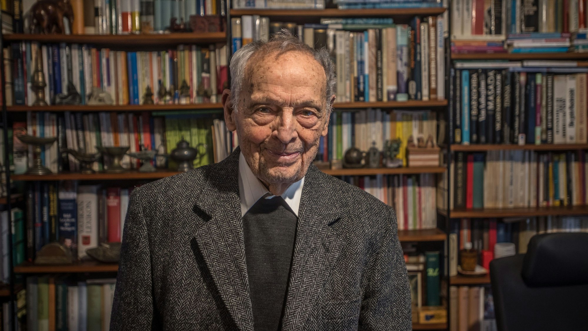 Monsignore Prälat Erich Läufer im Arbeitszimmer. Er trägt einen grauen Anzug und lächelt.