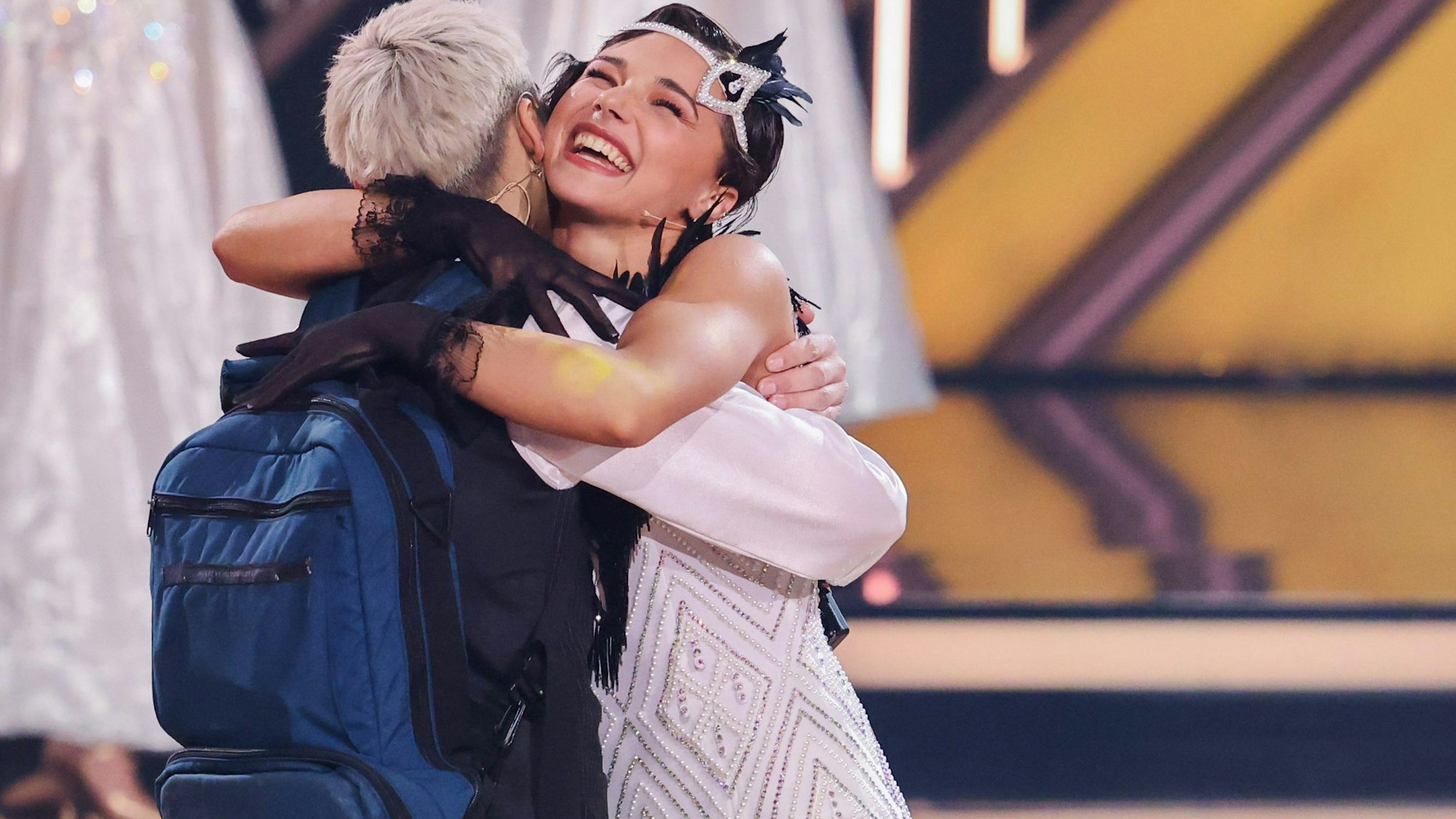 Tony Bauer trägt einen Rucksack für seine Ernährung, als er von seiner Tanzpartnerin Anastasia Stan in der Kennenlernshow umarmt wird.