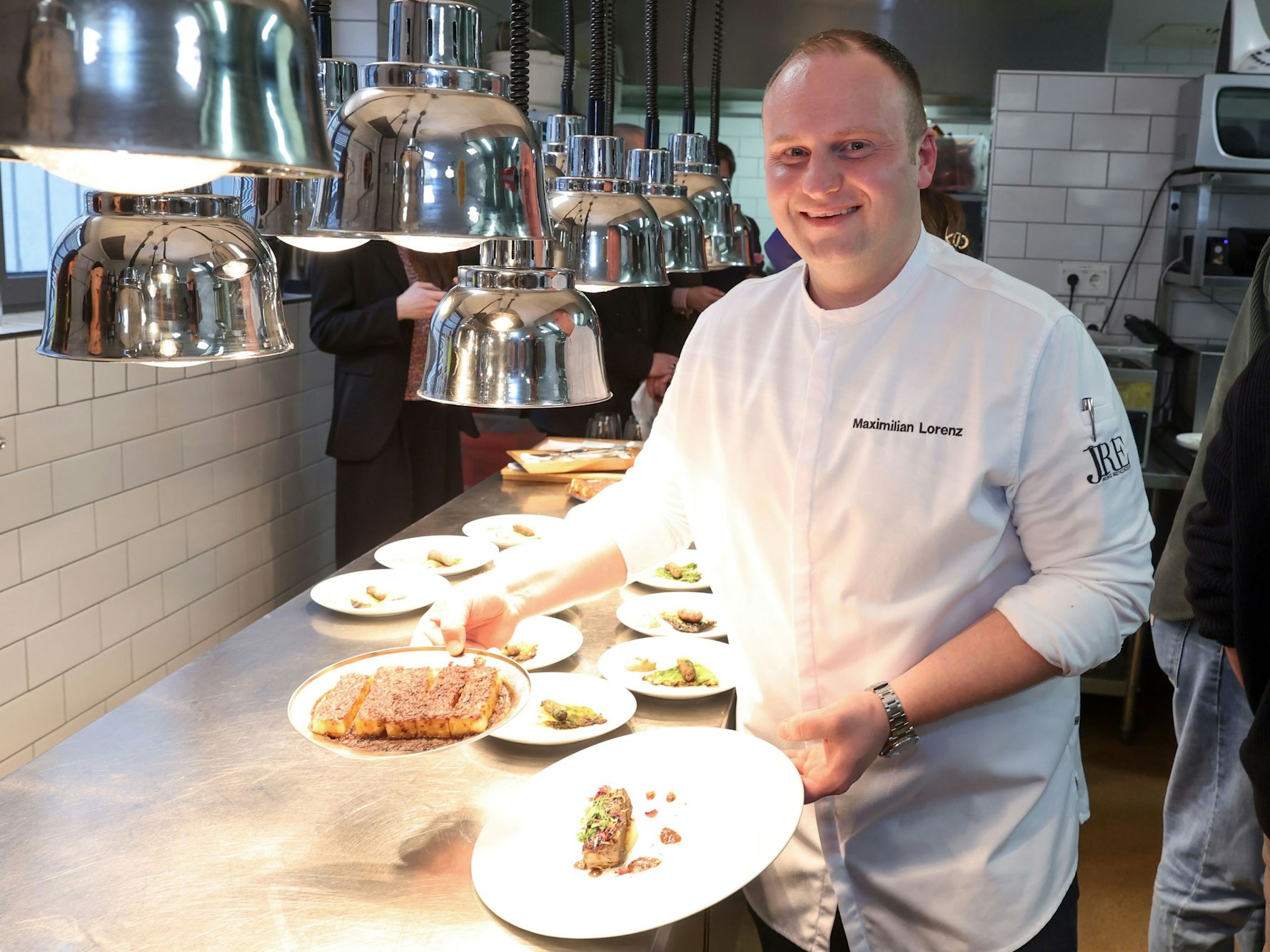 Koch Maximilian Lorenz hält zwei Teller mit Sauerbraten in seiner Restaurantküche in die Kamera.