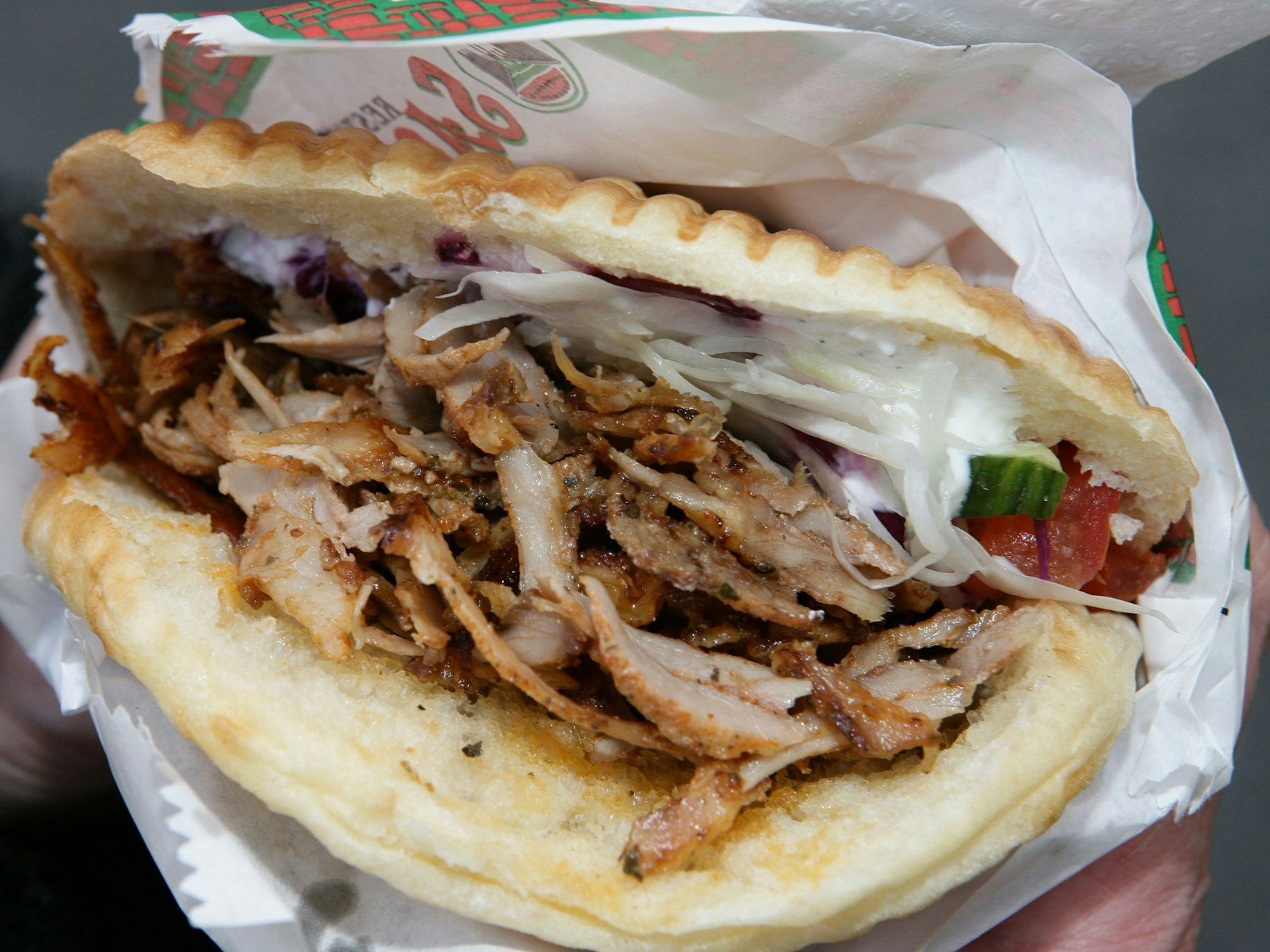 Ein Döner wird in einer Hand gehalten.
