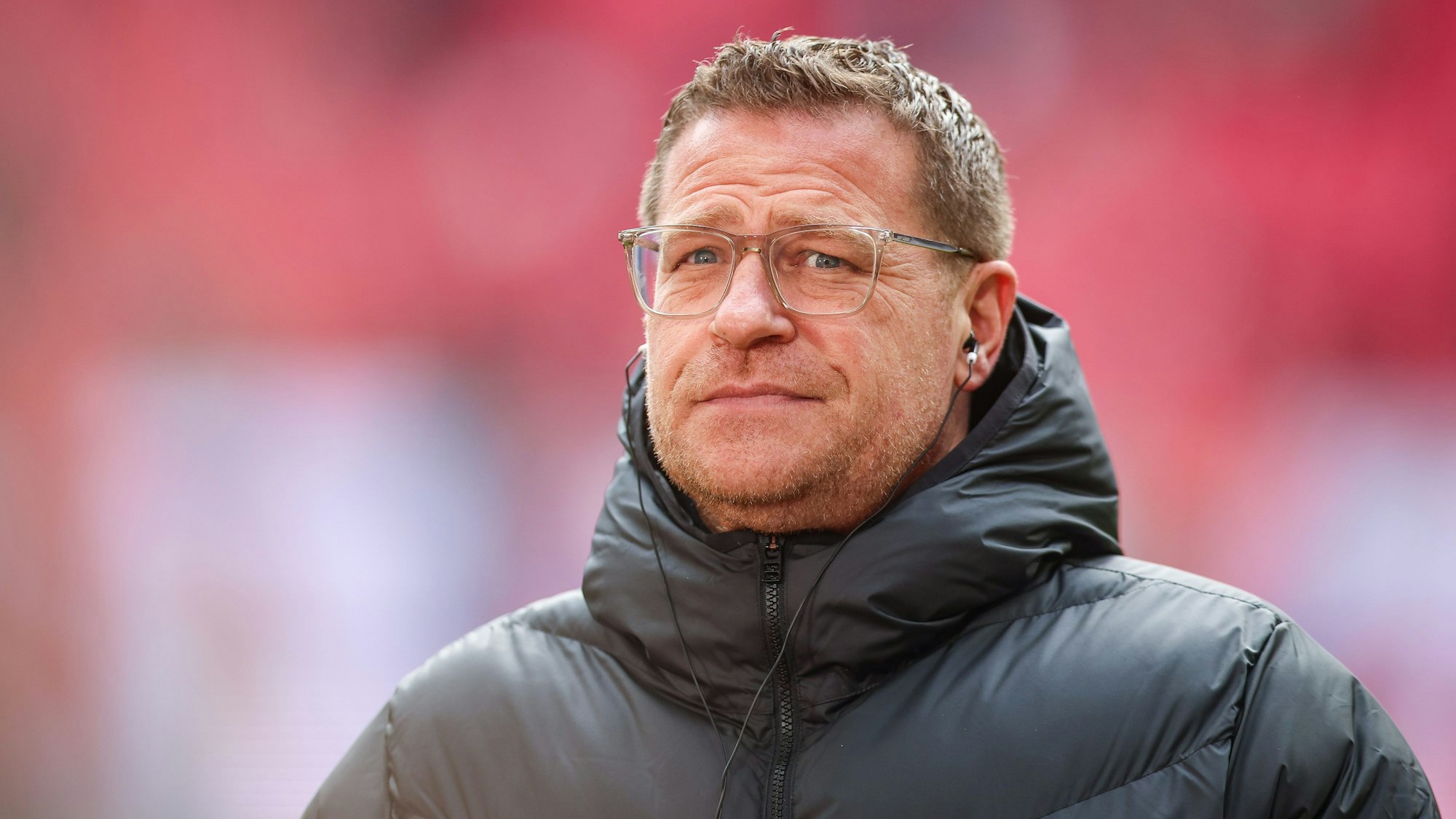 Max Eberl trägt während eines TV-Interviews Kopfhörer im Ohr.