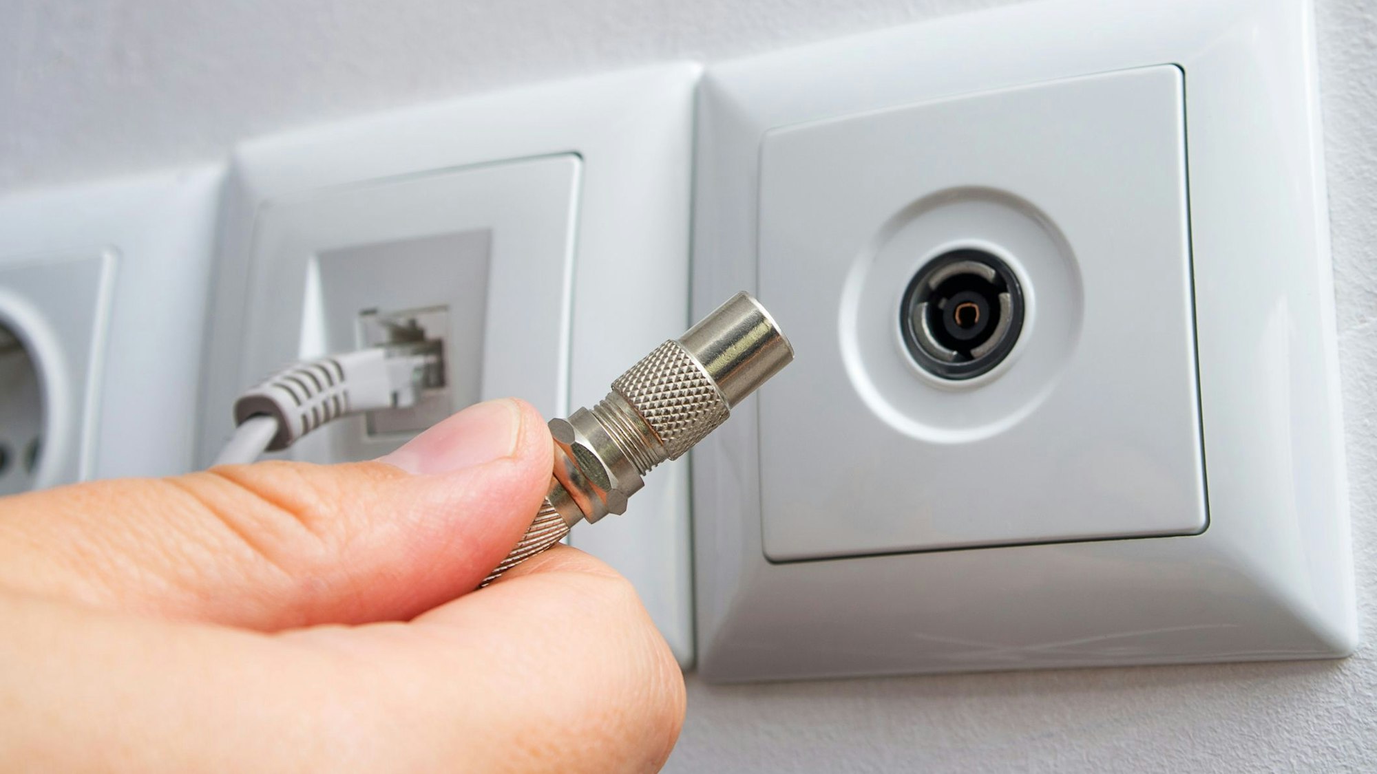 Ein Mann steckt ein Fernsehkabel ein.