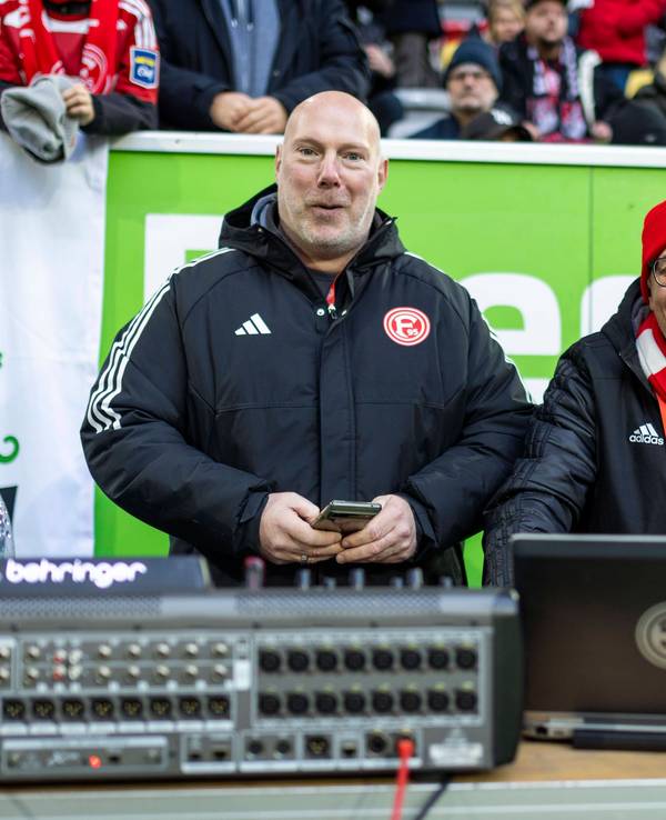 Fortuna Düsseldorfs Stadion-DJ Marcus „Opa“ Haefs und Techniker Carsten Johns lächeln beim Heimspiel gegen Holstein Kiel in die Kamera.