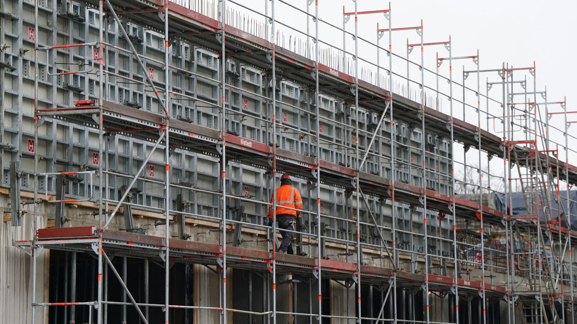 Ein Bauarbeiter geht über ein Baugerüst auf einer Baustelle.