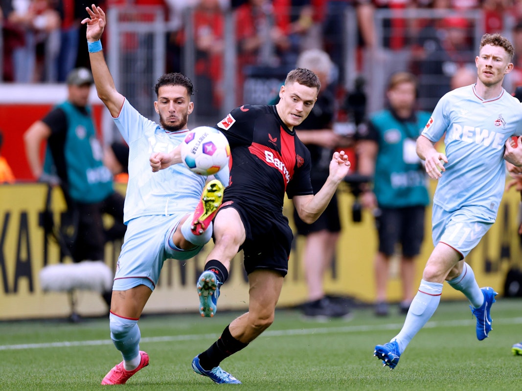 Leart Pacarada und Florian Wirtz beim Spiel zwischen Bayer Leverkusen und dem 1. FC Köln im Duell um den Ball.