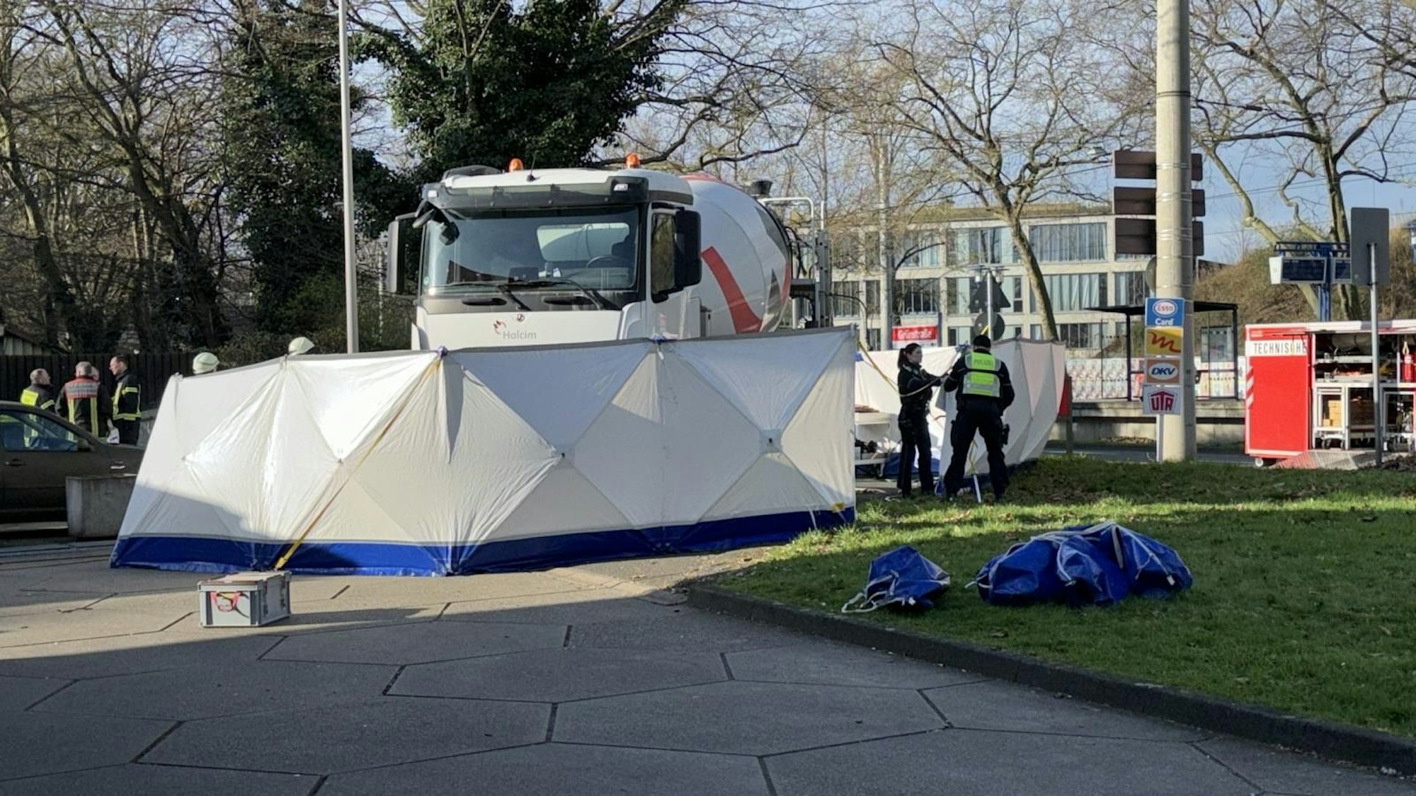 Ein Betonmischer steht an einer Tankstelle, ein Sichtschutz ist aufgebaut, mehrere Einsatzkräfte stehen dort.
