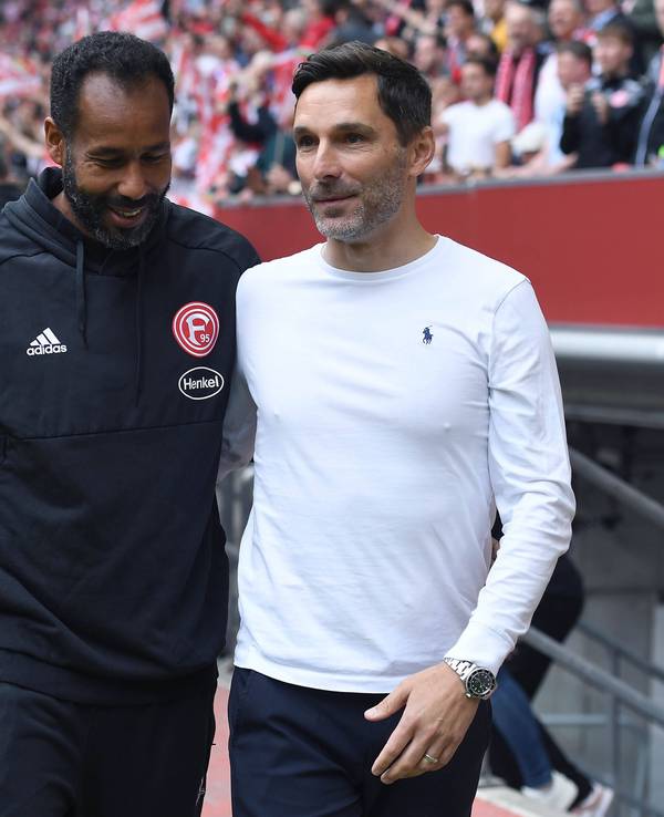 Fortuna Düsseldorfs Trainer Daniel Thioune und Hannover-Coach Stefan Leitl anehmen sich am Spielfeldrand in den Arm.