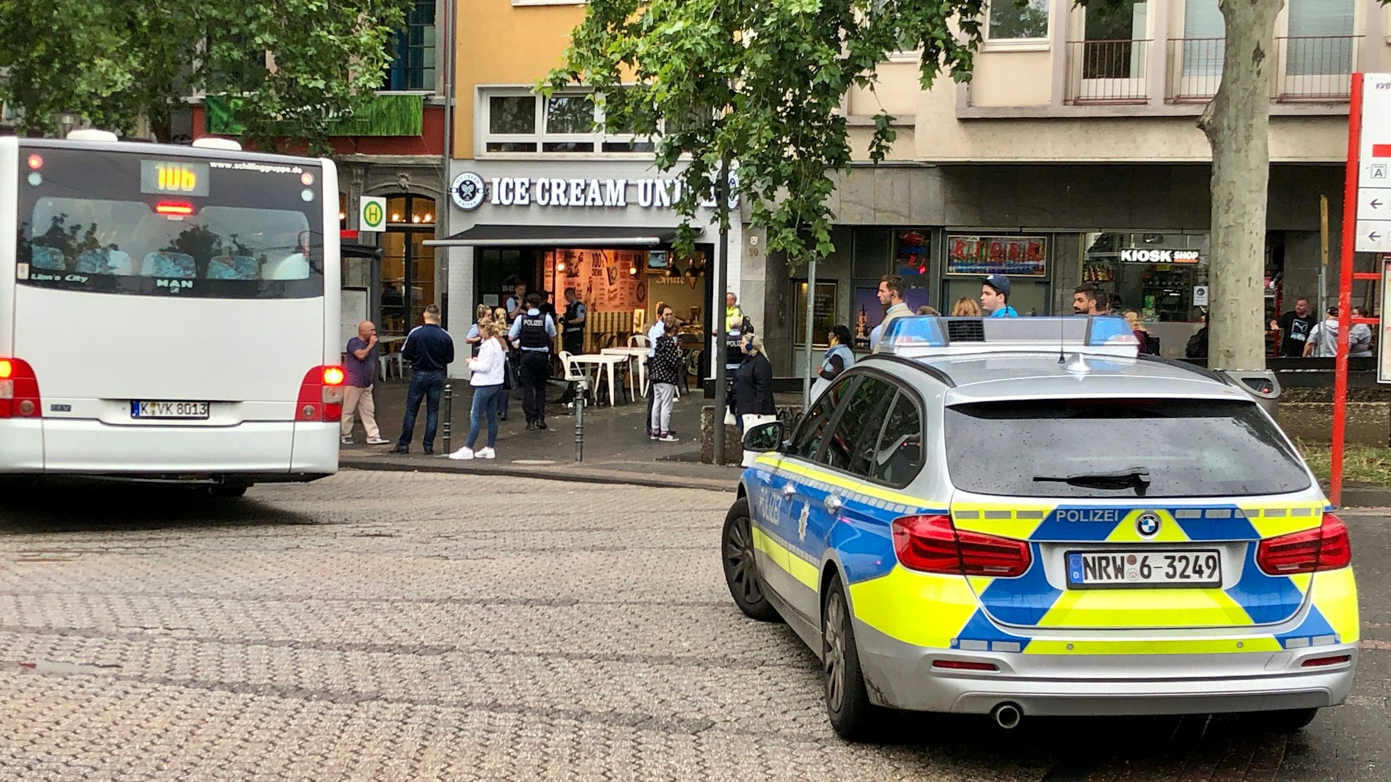 Foto eines Polizeieinsatzes in Köln, daneben ist ein weißer Bus zu sehen.