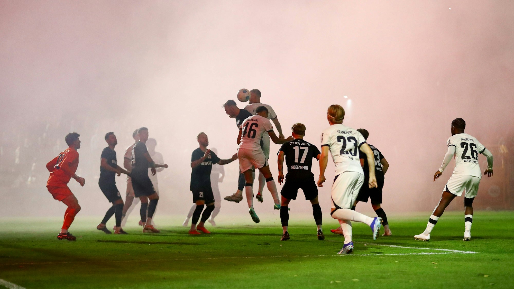 Spieler von Chemie Leipzig und Eintracht Frankfurt im dichten Rauch.