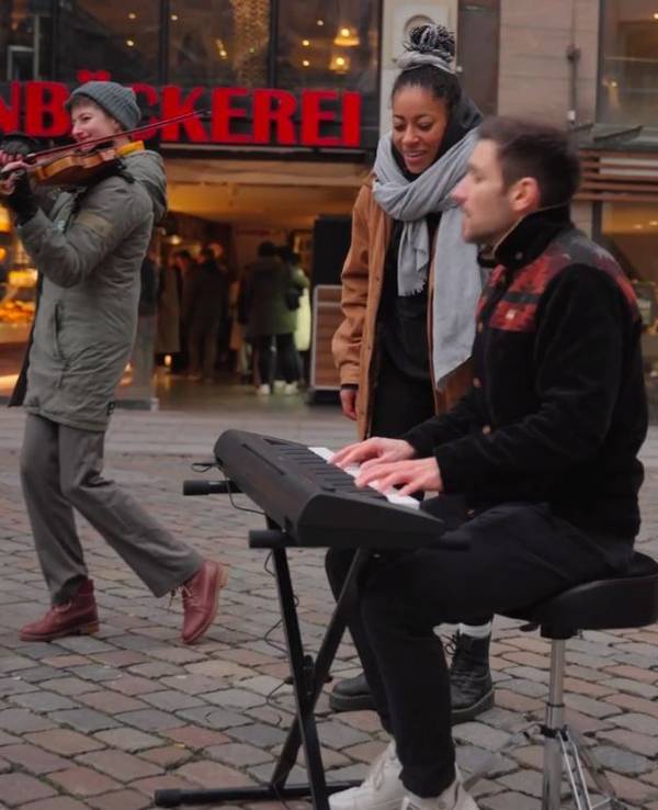 Der Kölner Sänger Julian Adler, Sängerin Diana Ezerex und Violinistin Felicitas Fischbein spielen auf einem Platz in Hamburg.