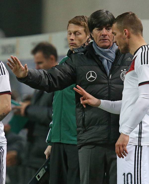 Lukas Podolski erhält vor seiner Einwechslung von Joachim Löw letzte Anweisungen. Max Kruse schaut interessiert zu.