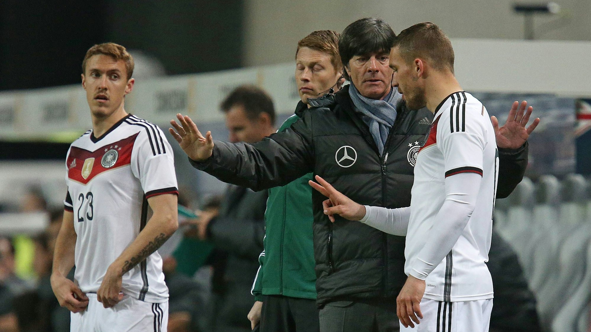 Lukas Podolski erhält vor seiner Einwechslung von Joachim Löw letzte Anweisungen. Max Kruse schaut interessiert zu.