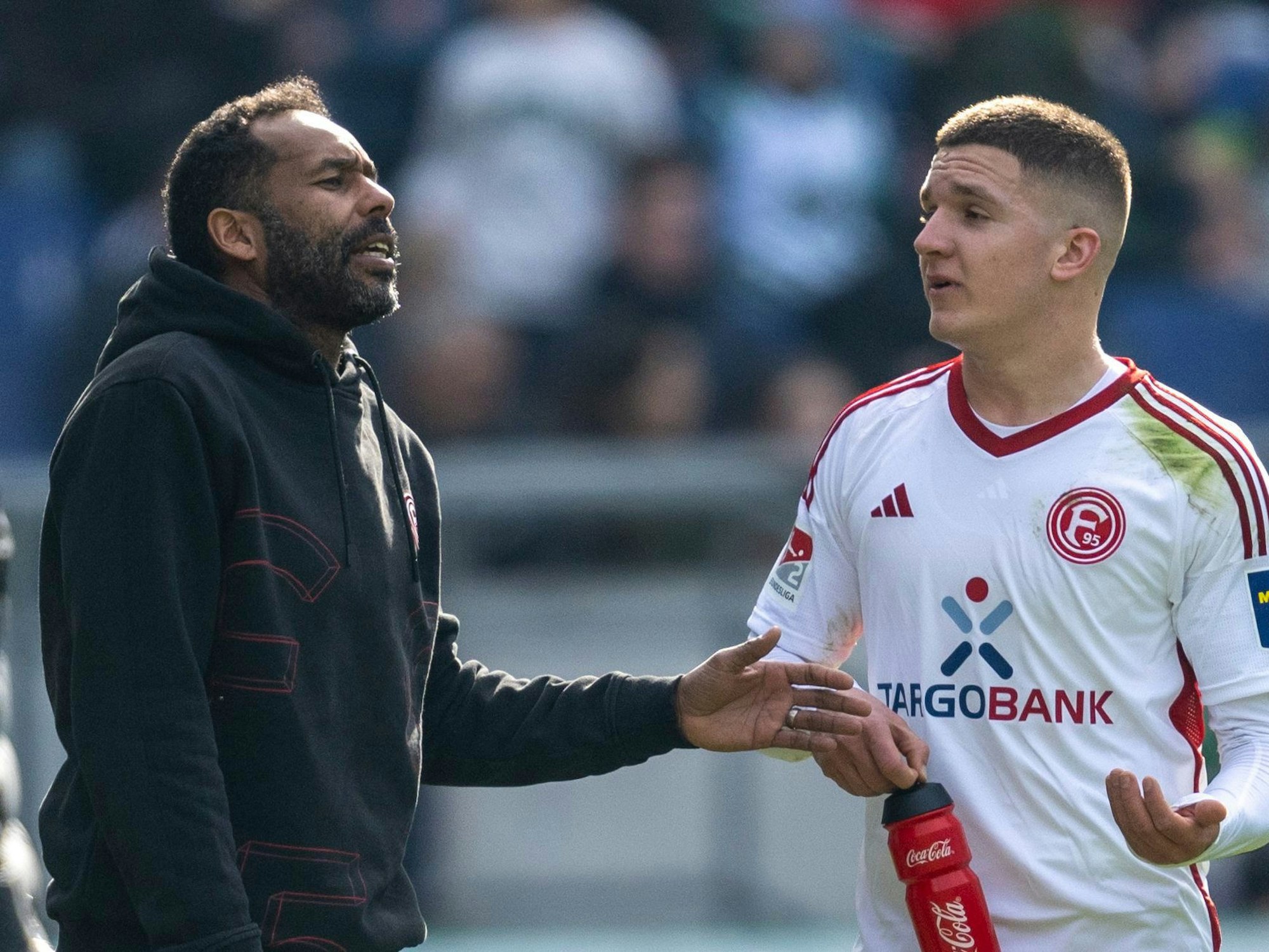 Düsseldorfs Trainer Daniel Thioune (l.) spricht am 2. März 2024 mit Fortuna-Profi Christos Tzolis.