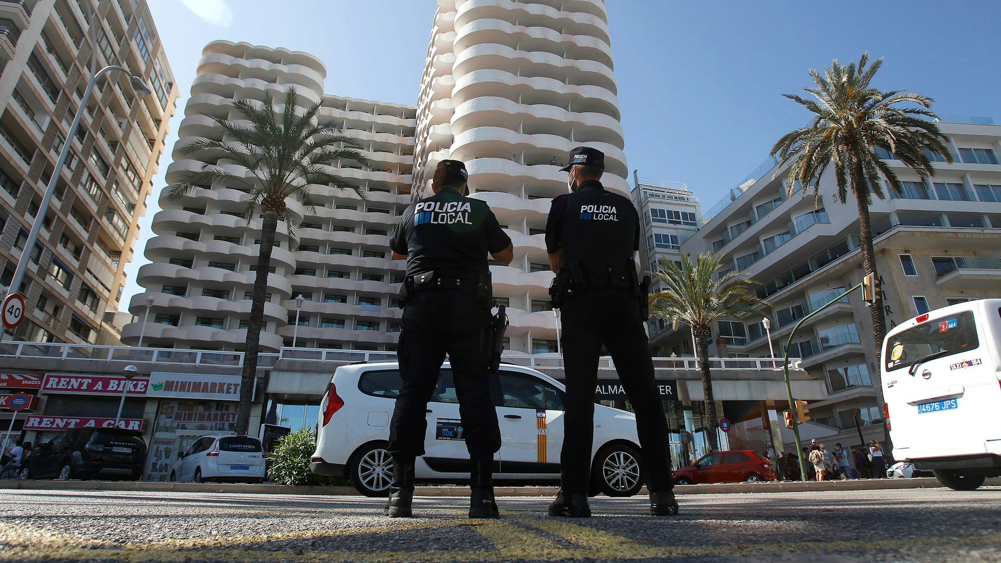 Zwei Polizisten stehen im Einsatz vor dem Hotel auf Mallorca, in dem mehr als 200 Schülerinnen und Schüler in Corona-Zwangsquarantäne gesetzt wurden.