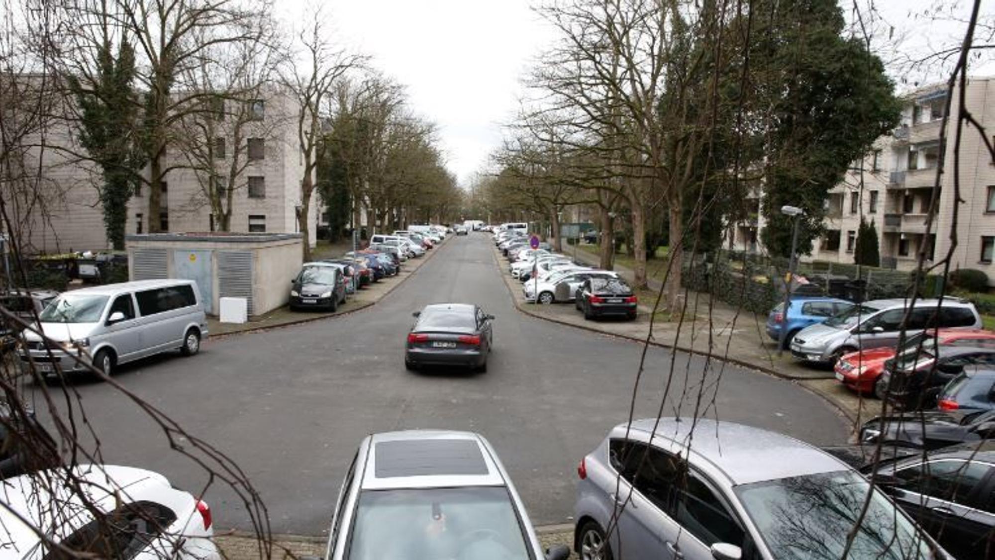 Blick auf eine Straße mit diversen geparkten und fahrenden Autos.