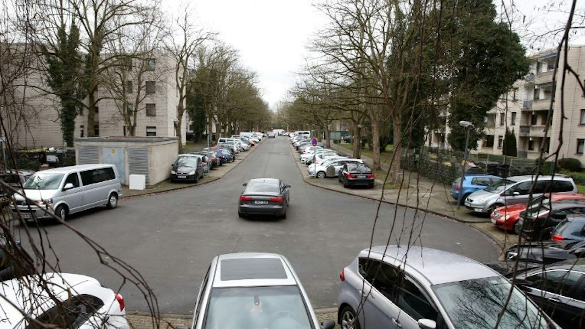 Blick auf eine Straße mit diversen geparkten und fahrenden Autos.