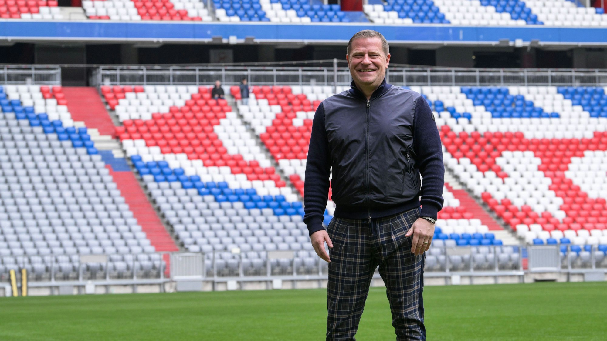 Max Eberl steht in karierter Hose auf dem Rasen der Allianz-Arena.
