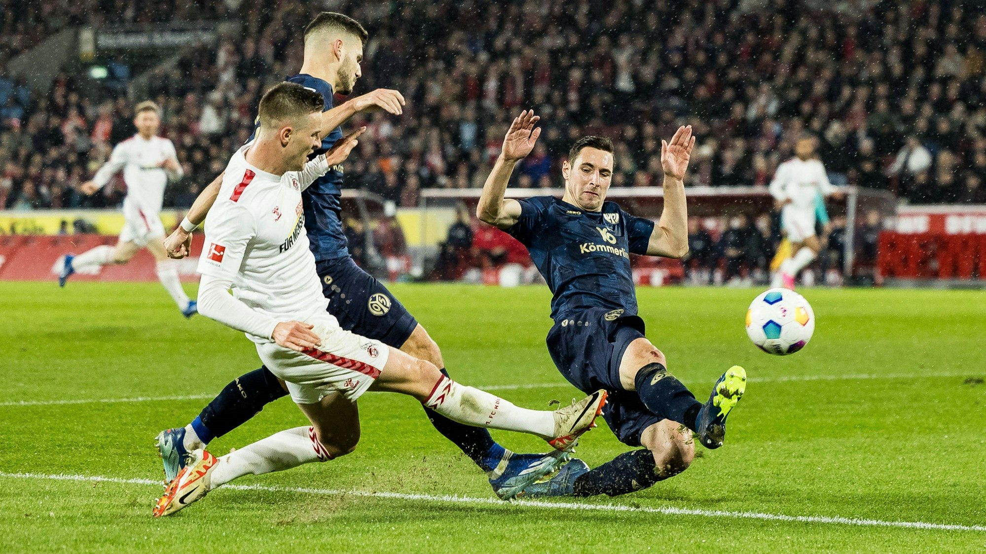 Rasmus Carstensen vom 1. FC Köln im Duell um den Ball mit zwei Gegenspielern von Mainz 05.