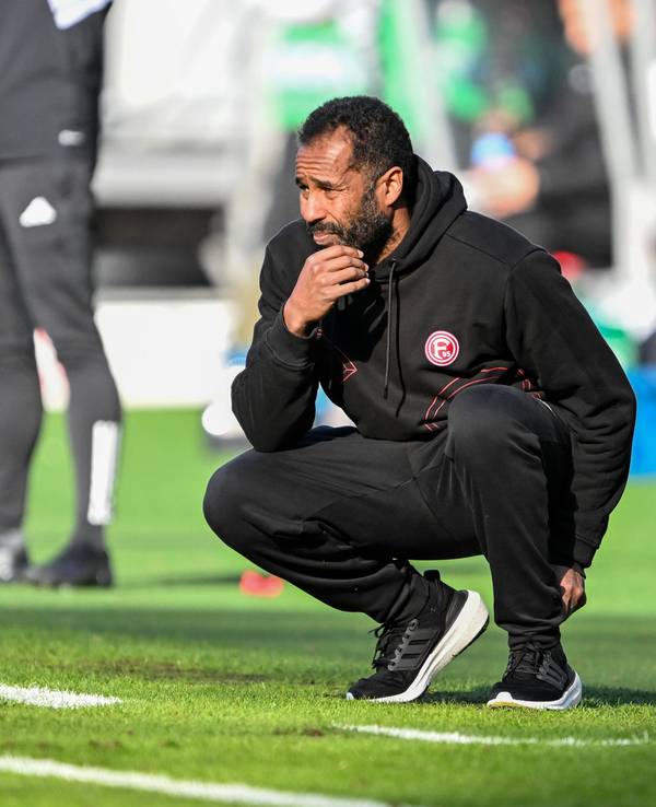 Daniel Thioune geht beim Spiel von Fortuna Düsseldorf nachdenklich in die Hocke.