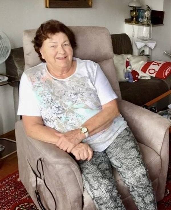 Eine Frau sitzt in einem Sessel in ihrer Wohnung.