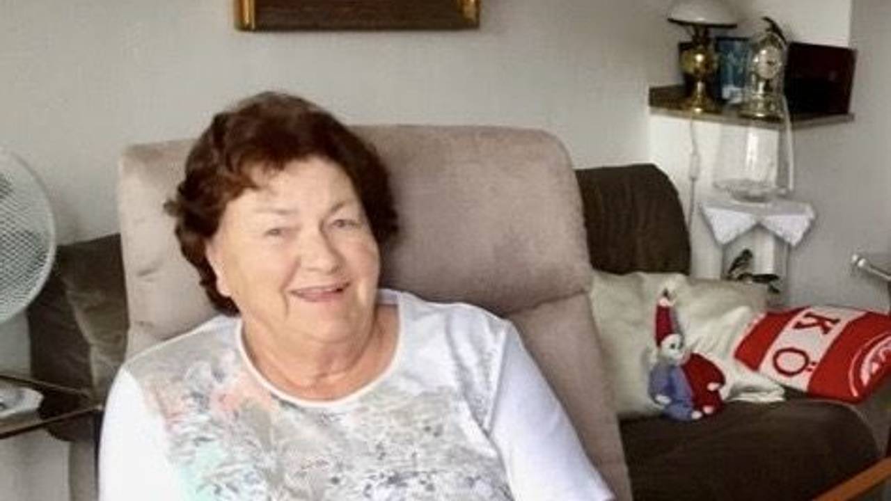 Eine Frau sitzt in einem Sessel in ihrer Wohnung.