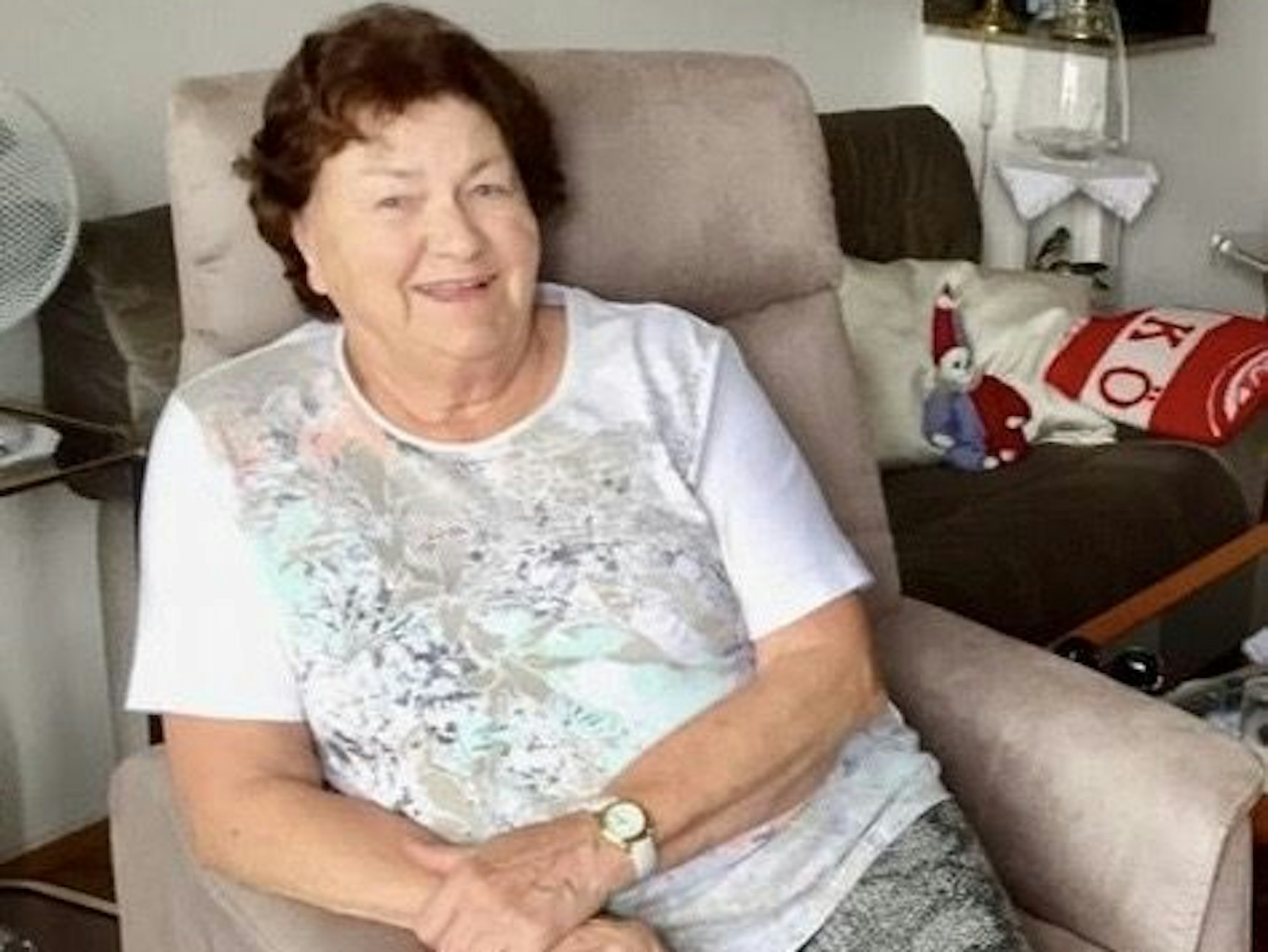 Eine Frau sitzt in einem Sessel in ihrer Wohnung.