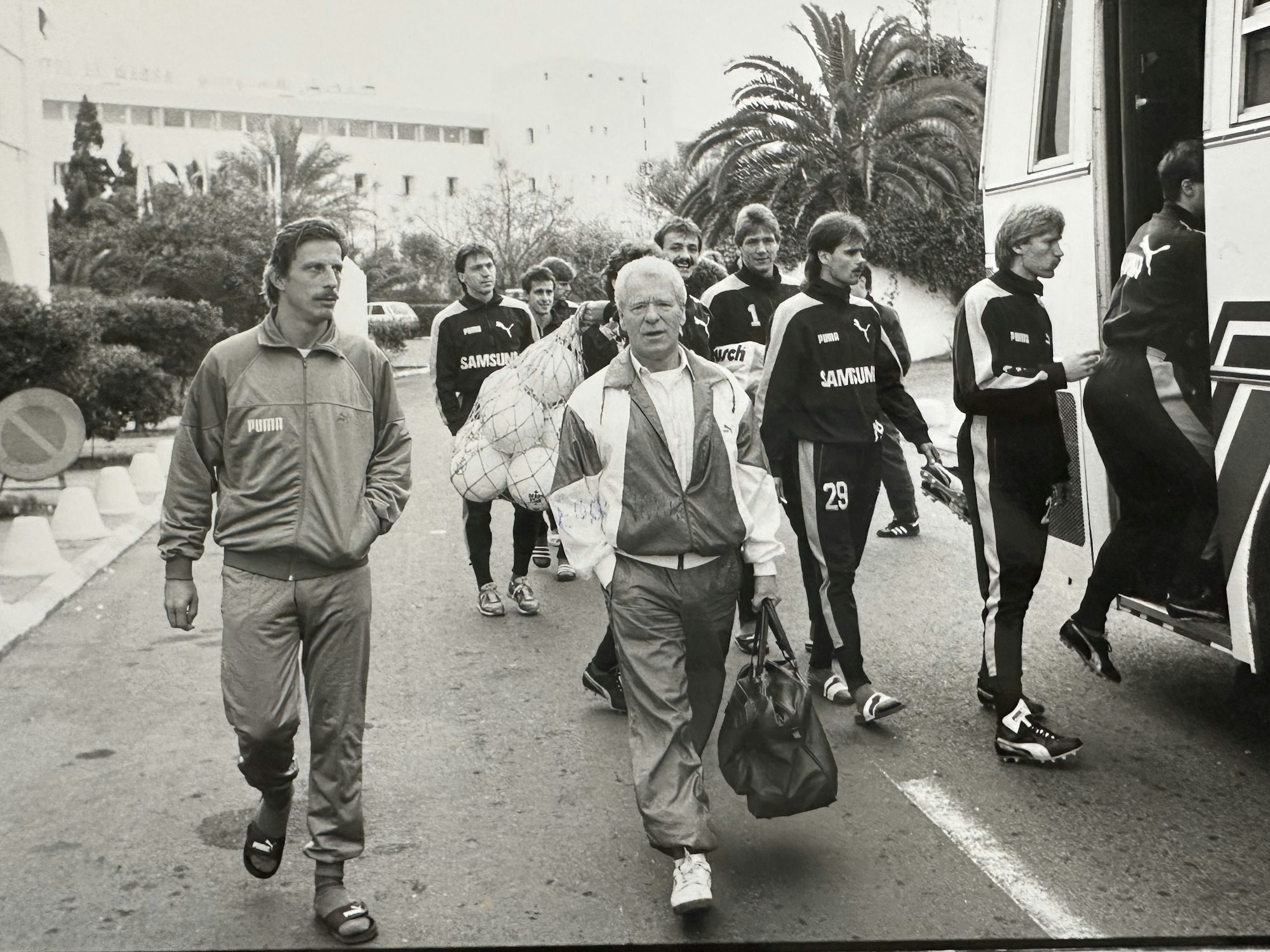 Zwei Männer laufen neben einem Bus her.