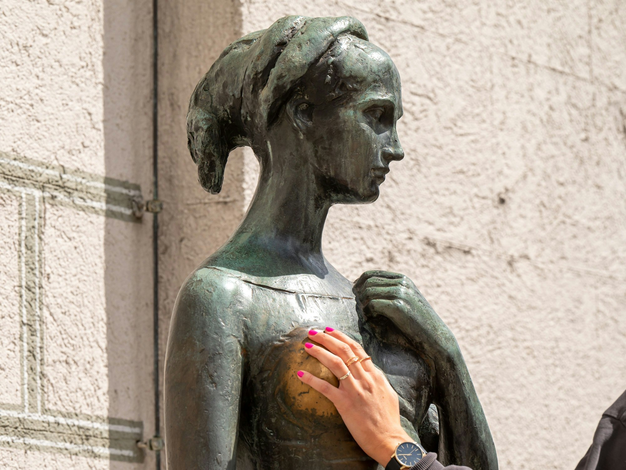 Eine Frau greift dem Bronzedenkmal Julia am Alten Rathaus an die Brust. Viele reiben an Julias Brust, um Glück in der Liebe zu bekommen.