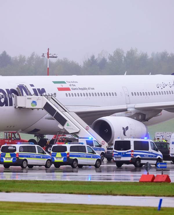Einsatzfahrzeuge der Polizei stehen vor einem Flugzeug der Iran Air.