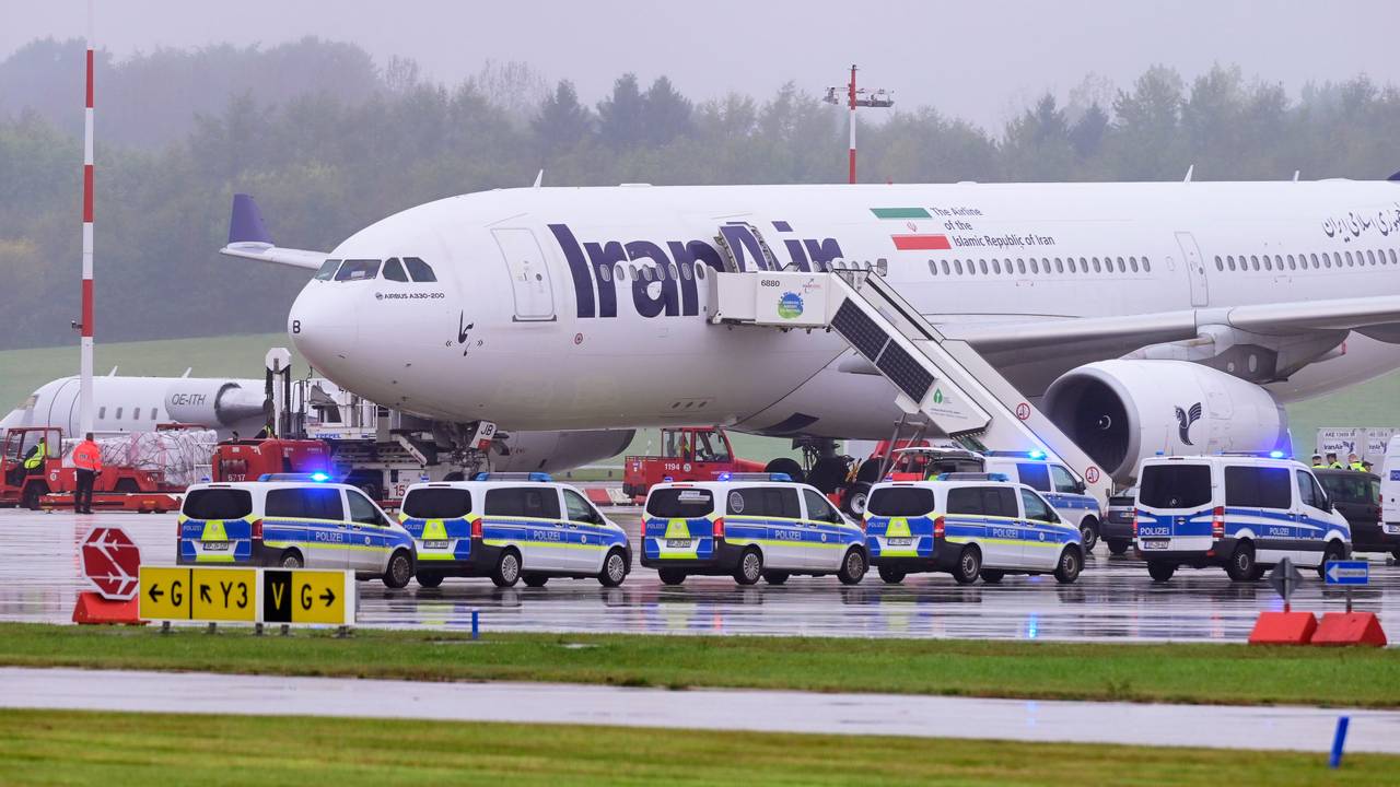 Einsatzfahrzeuge der Polizei stehen vor einem Flugzeug der Iran Air.