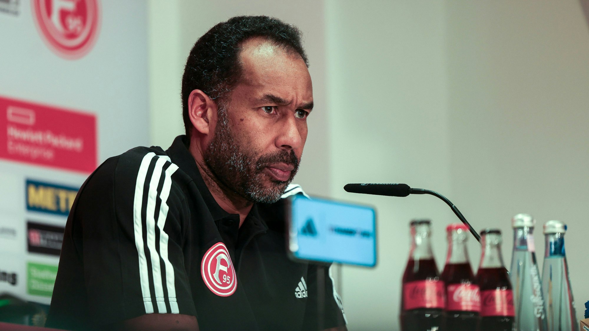 Fortuna Düsseldorfs Trainer Daniel Thioune sitzt bei der Pressekonferenz auf dem Podium.