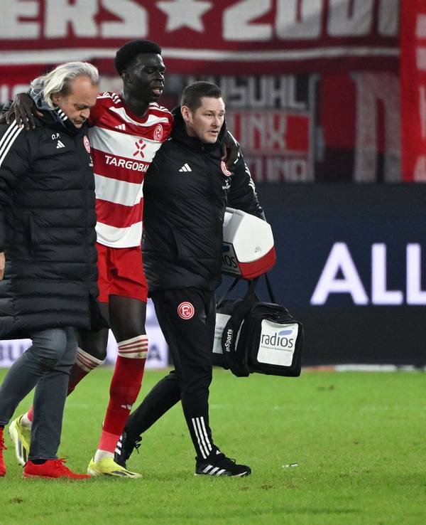 Fortuna Düsseldorfs Joshua Quarshie verlässt beim Spiel gegen den Hamburger SV gestützt von Betreuern den Platz.