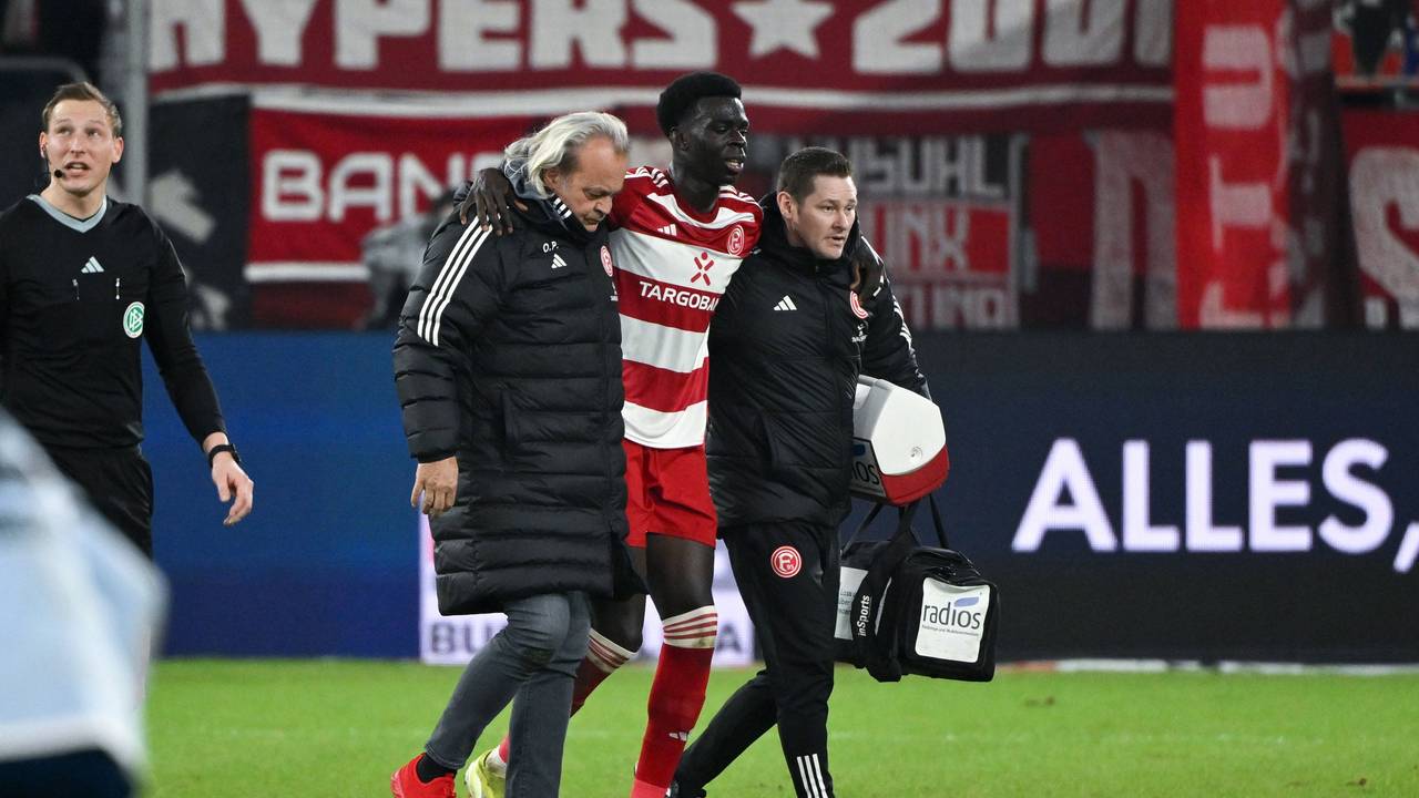 Fortuna Düsseldorfs Joshua Quarshie verlässt beim Spiel gegen den Hamburger SV gestützt von Betreuern den Platz.