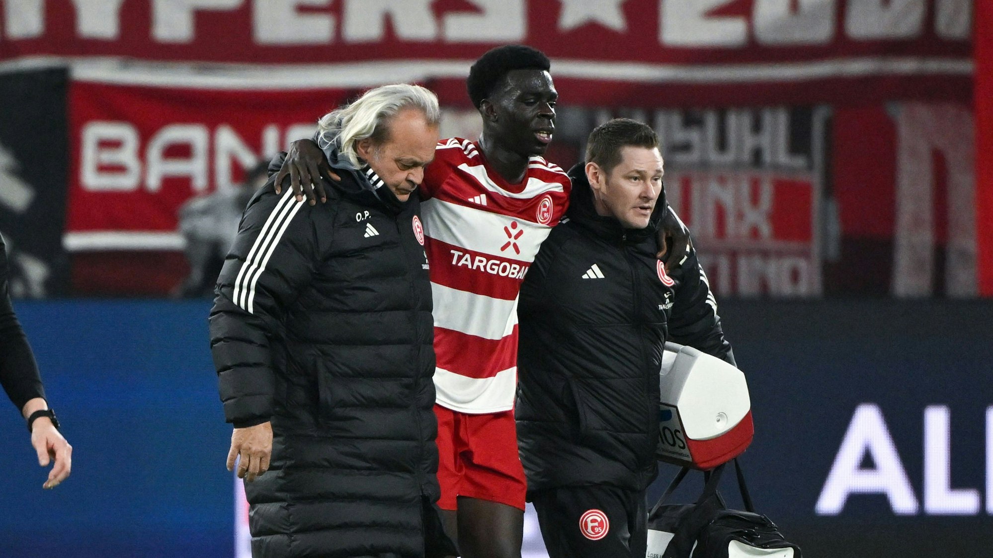 Fortuna Düsseldorfs Joshua Quarshie verlässt beim Spiel gegen den Hamburger SV gestützt von Betreuern den Platz.