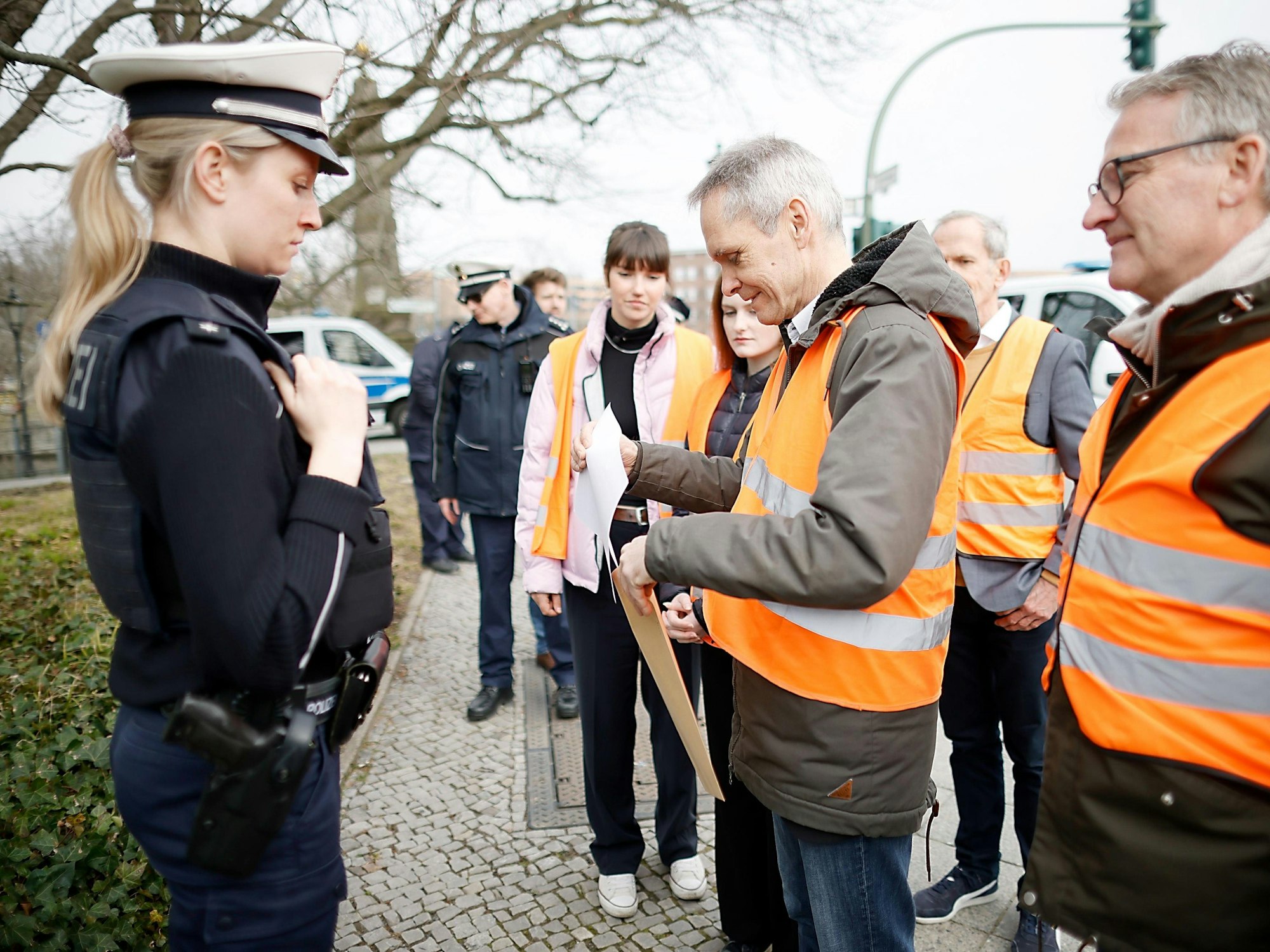 Drei Vertreter der Letzten Generation übergeben einer Polizistin ein Schreiben.
