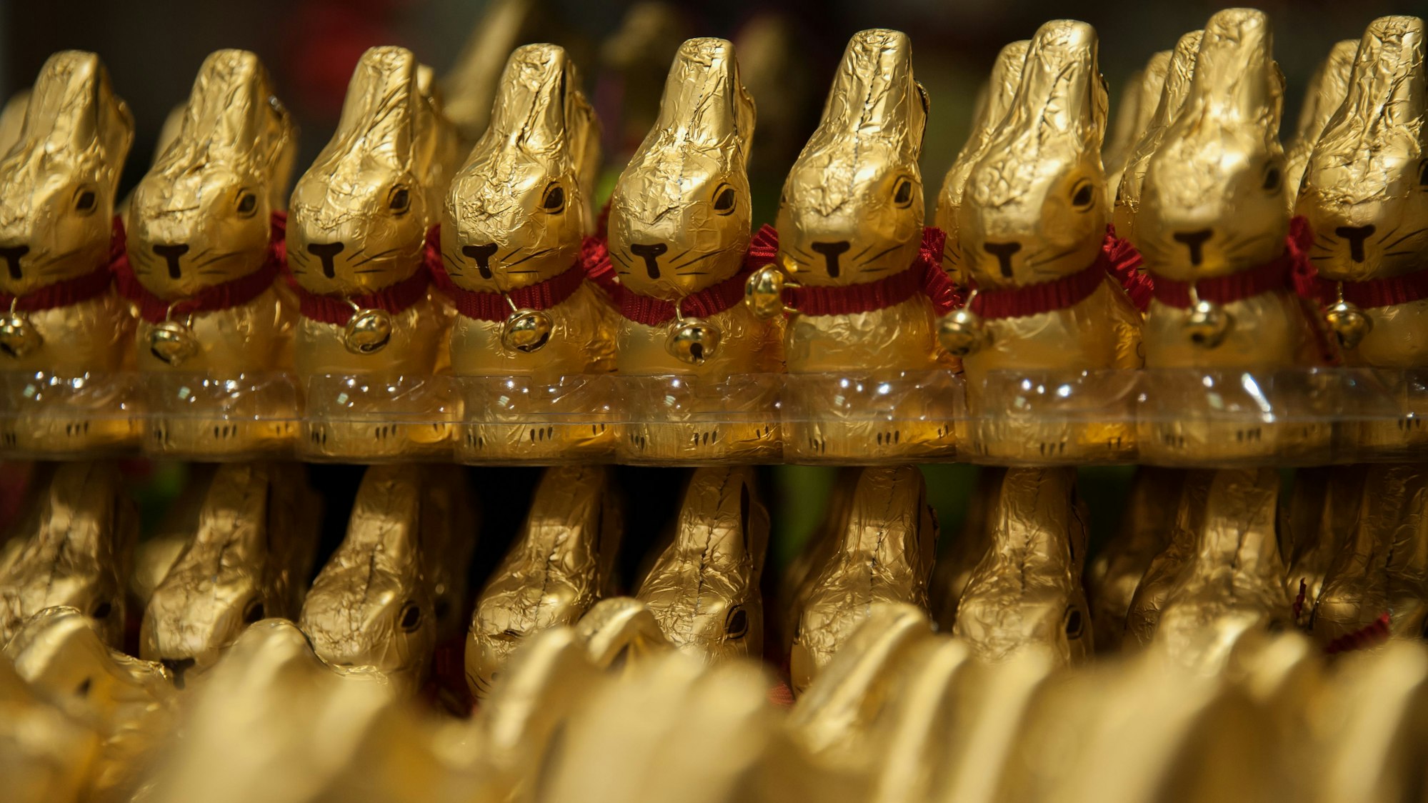 Osterhasen aus Schokolade aufgereiht in einem Supermarkt.
