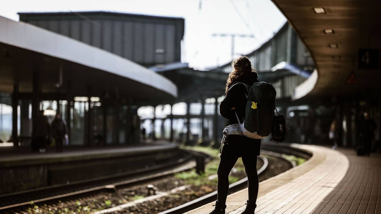 Eine Frau mit Rucksack steht auf dem Bahnsteig.