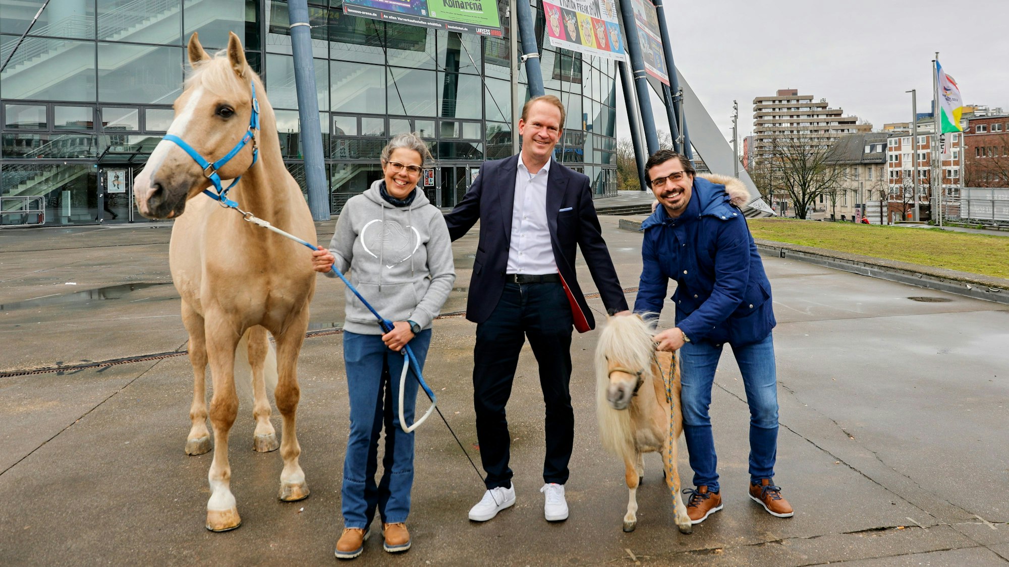 Arena-Chef Stefan Löcher (M.) steht mit Pferdepflegerin Carmen Ortega und Dressurreiter Filipe Fernandes sowie dem Show-Pferd „Gorgorito“ und Pony „Arno“ vor der Lanxess Arena.